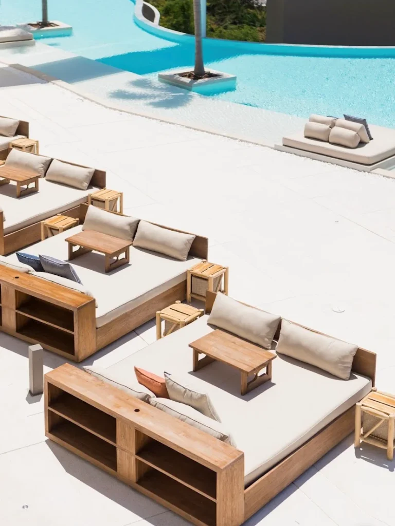 Contemporary reclaimed teak outdoor daybeds and sofas at Fira Beach Club in Phuket overlooking a luxury pool and tropical landscape.