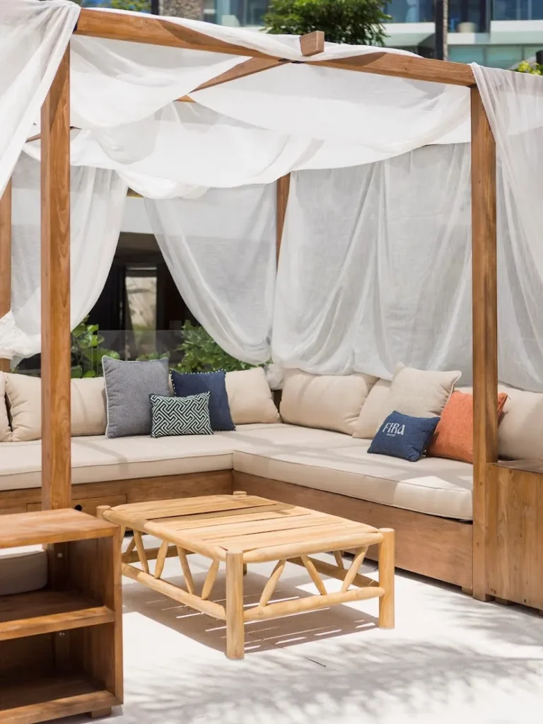 Modern outdoor cabana with contemporary recycled teak wood furniture and cream cushions at Fira Beach Club, Phuket, Thailand.