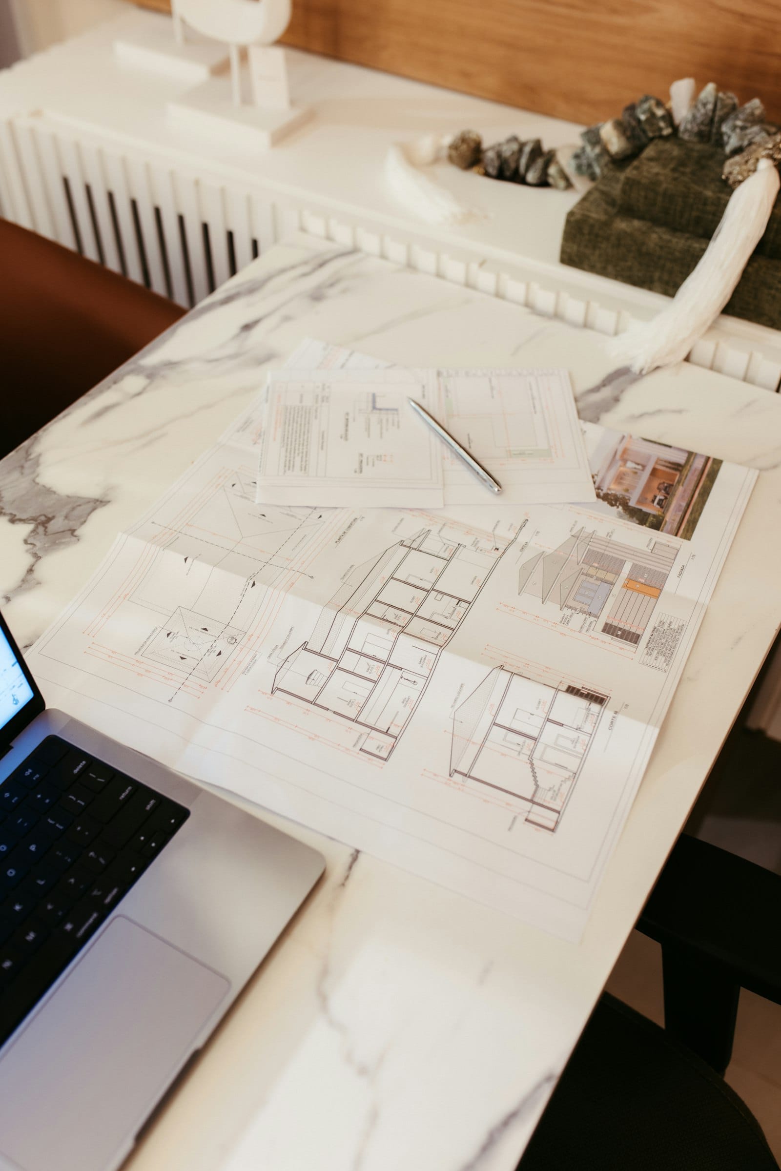 Architectural drawings and CAD files on a desk, representing the specification review stage of a custom teak furniture order